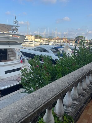 Ein Yachthafen mit mehreren angestaubten Yachten, eine Steinbalustrade im Vordergrund und Gebäude im Hintergrund.