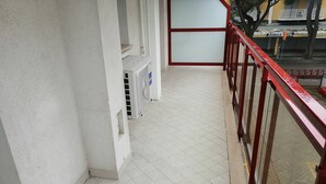 A corridor with tiled flooring, a red railing, and air conditioning units. - Apartment 'Acapulco Residence 201' with Shared Pool and Private Terrace (Lido di Jesolo)