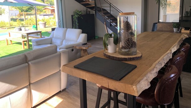 Ein modernes Wohnzimmer mit einem Holzesstisch, einem weißen Sofa und einer Treppe.