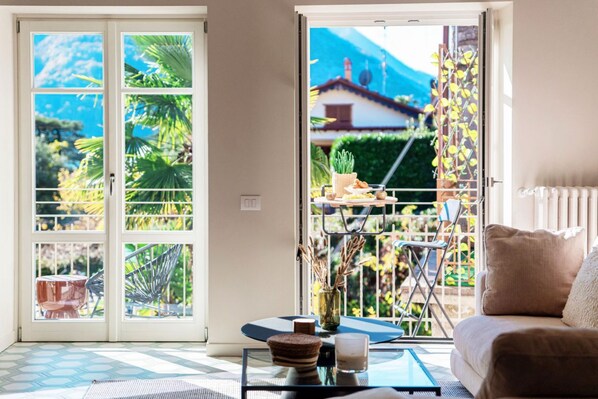 A room with a sliding glass door leading to a balcony with a view of a mountain and greenery. - “YOU MAY FIND YOURSELF IN A BEAUTIFUL HOUSE”Immerse yourself in the magical atmosphere of this ancient village. Here, you’ll breathe in an enchanting aura filled with tranquility and romantic glimpses. Not just a home, but a gem set in a quaint set (Laglio)