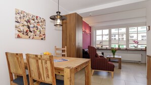 A dining area with wooden furniture, a pendant light, and a view of the outside through large windows. - Apartment Elli 02 (Rostock)