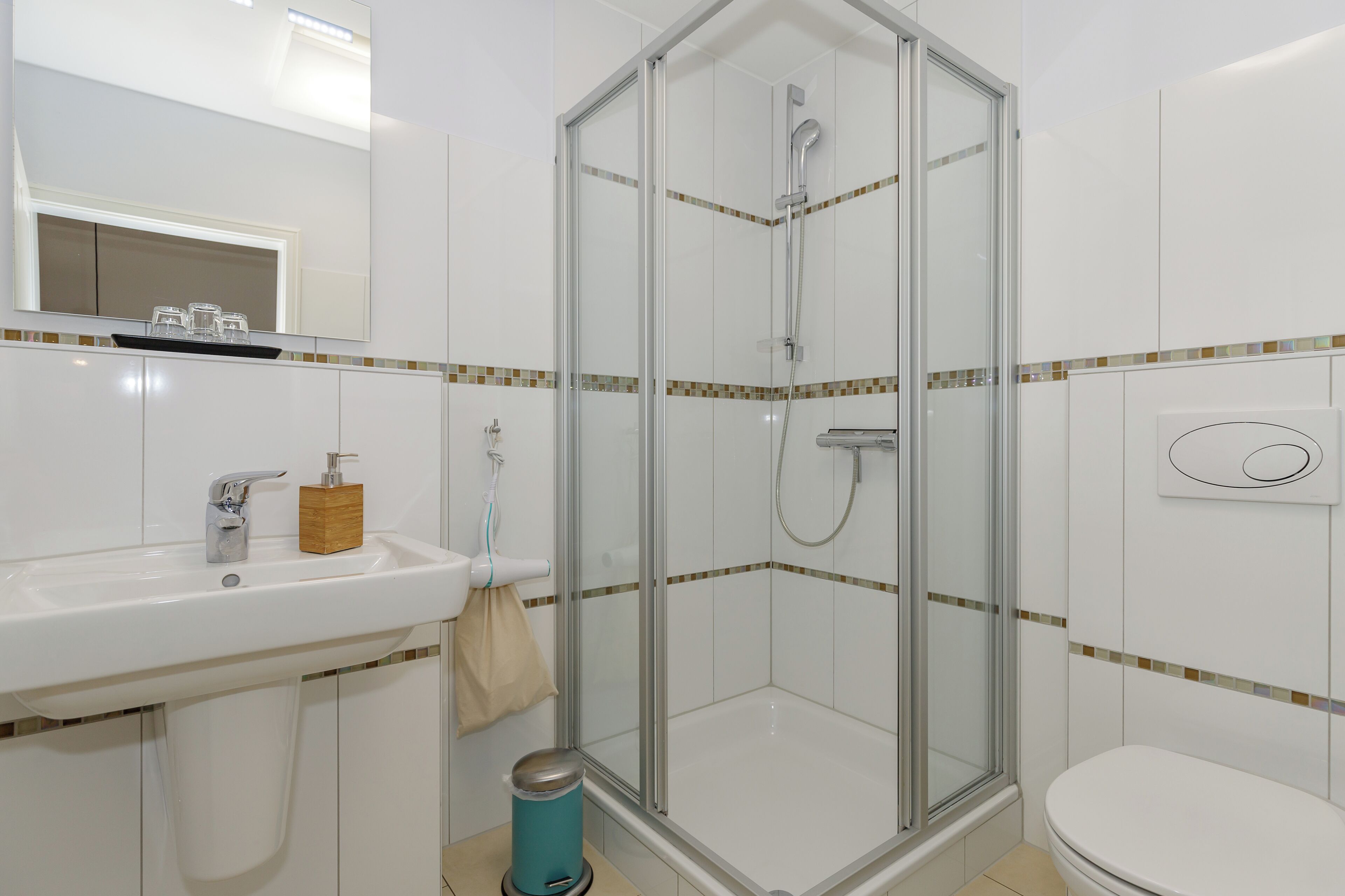 Une salle de bain avec une douche à parois de verre, un lavabo avec un miroir et des toilettes.