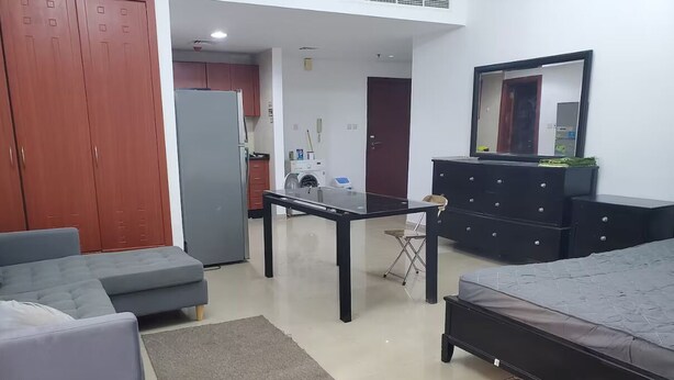 A living room with a sofa, a coffee table, a TV, a dresser, and a mirror. - Horizon Towers Residence Apartment  ★ (Ajman)