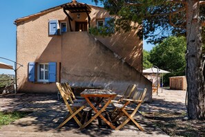 Uma casa de pedra rústica com uma mesa e cadeiras de madeira na varanda.