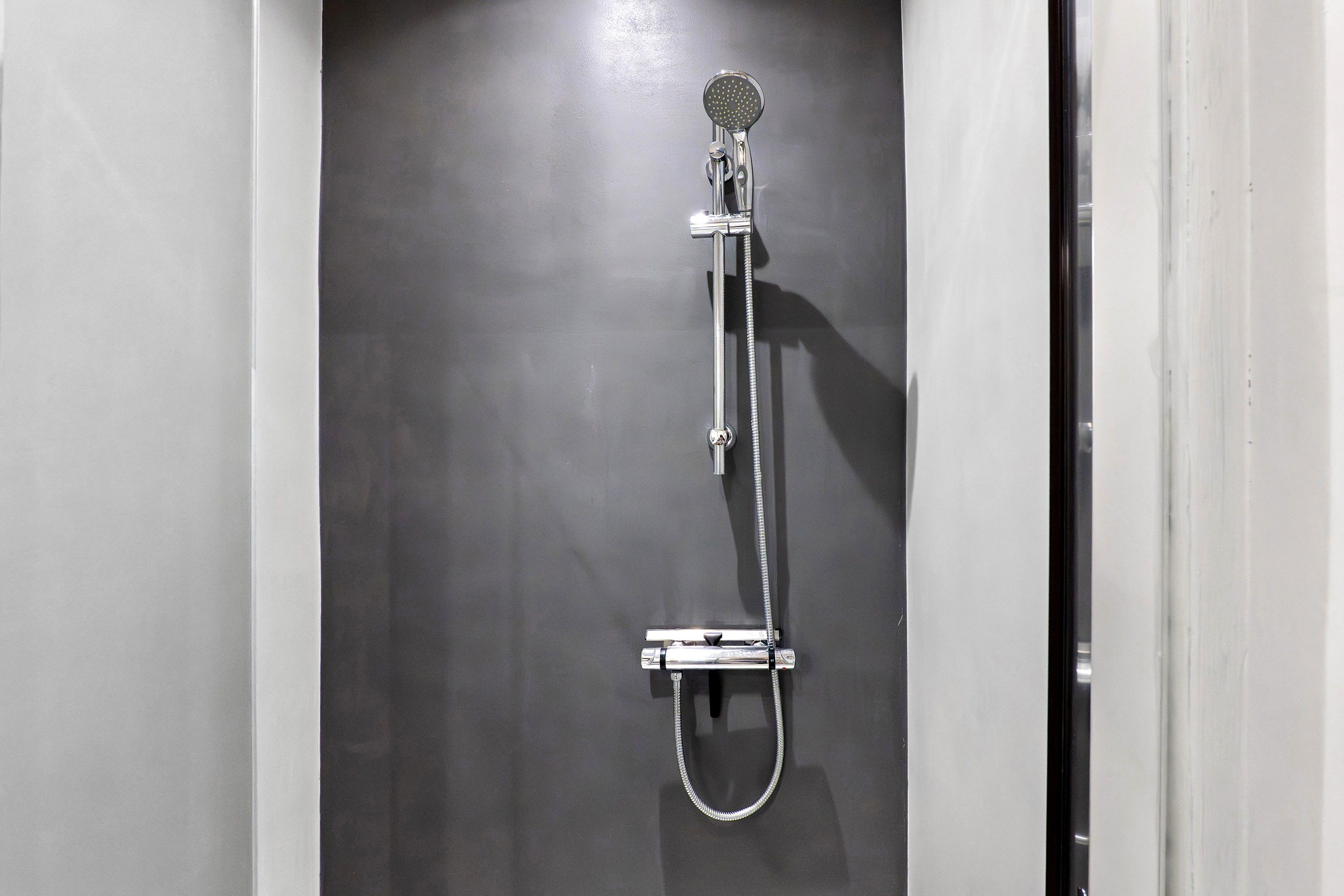 Eine Dusche mit Handbrause und fest installiertem Wasserhahn an der Wand.