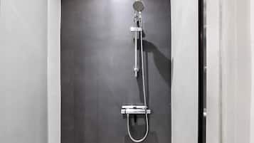 Ducha con cabezal de ducha de mano y grifo fijo en la pared.
