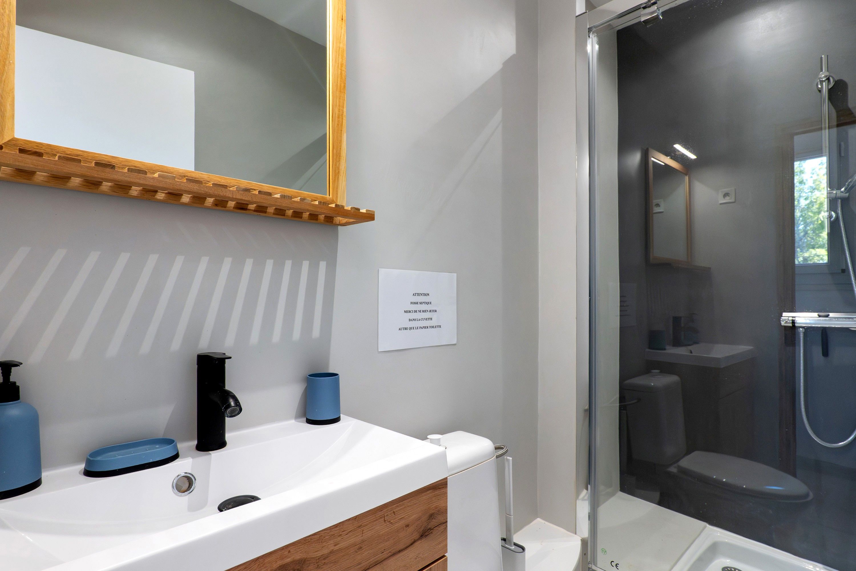 Une salle de bain avec un lavabo blanc, un miroir et un espace douche.