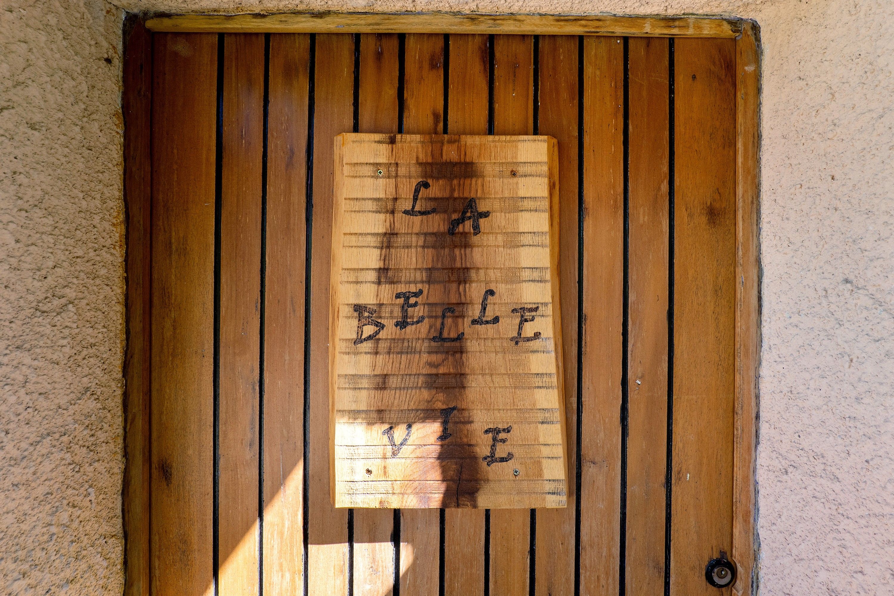 Una puerta de madera con un letrero escrito a mano que dice 'BE A BELIEVER'.