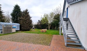Et boligområde med en trappe, der fører op til en hvid bygning, et overdækket område og et picnicbord.