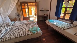 Une chambre avec deux lits, un ventilateur, un bureau et une fenêtre avec des rideaux.