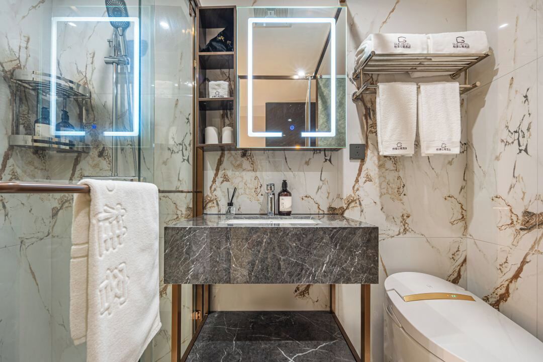 A bathroom with a marble sink, a glass shower enclosure, and a white bathtub.