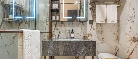 A bathroom with a marble sink, a glass shower enclosure, and a white bathtub.