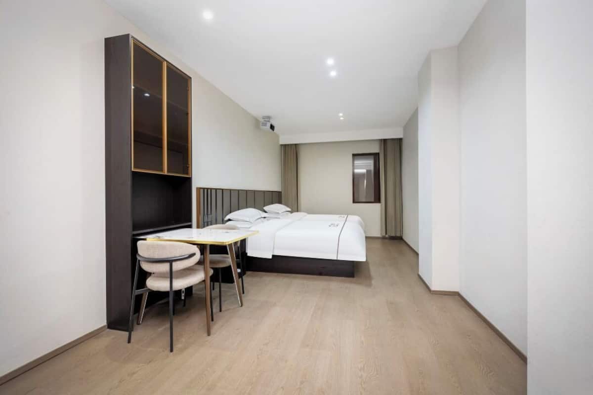 Una habitación de hotel con cama, escritorio, silla, armario y ventana.