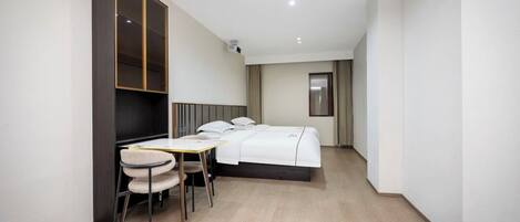 Una habitación de hotel con cama, escritorio, silla, armario y ventana.