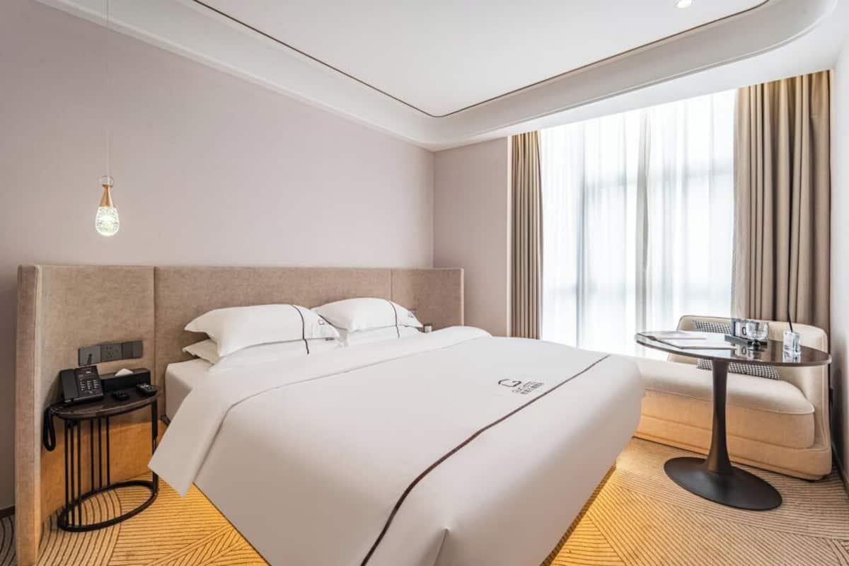 Habitación de hotel con una cama grande, mesita de noche y una pequeña mesa con una silla.