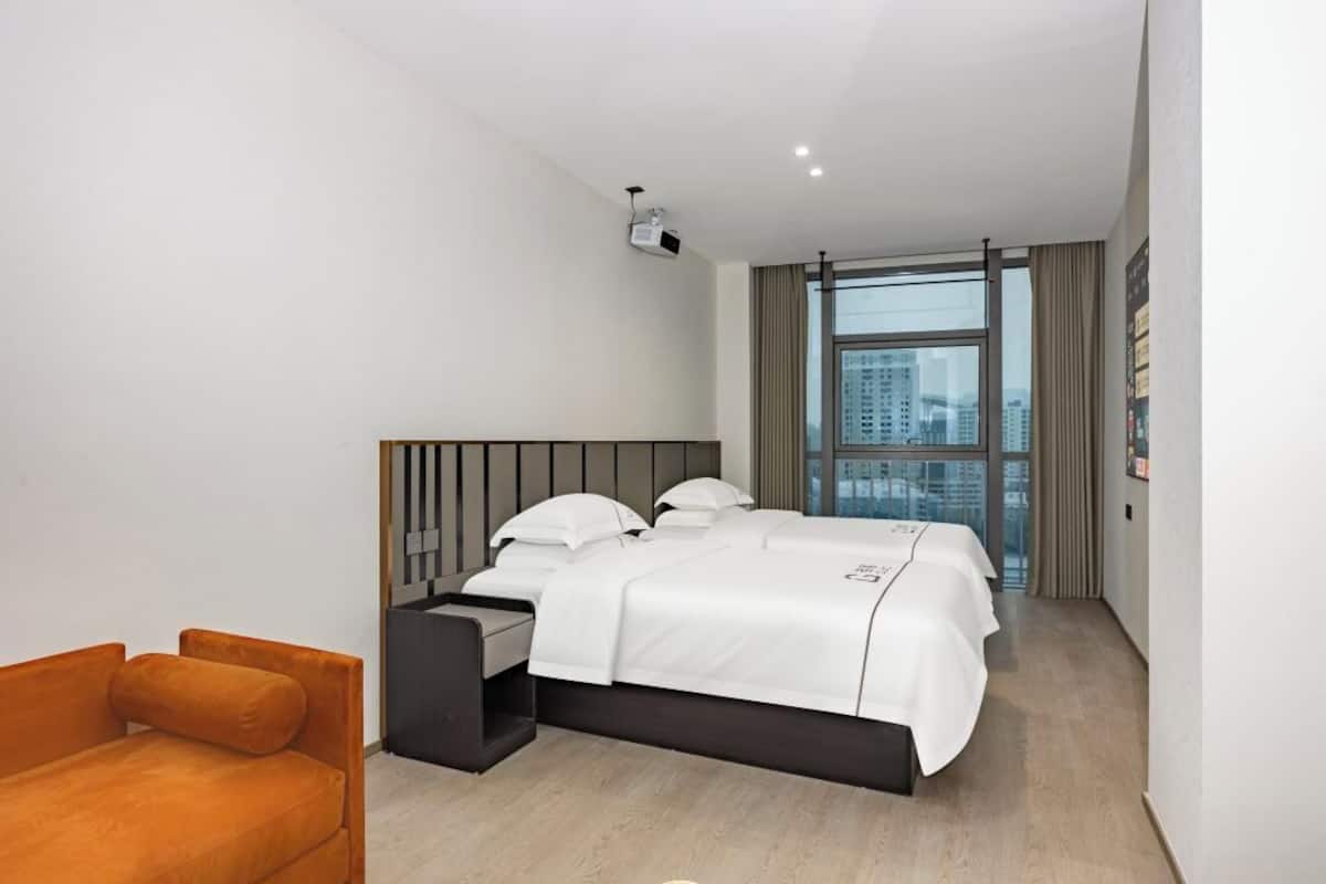 Una habitación de hotel moderna con una cama grande, un escritorio, una silla y un proyector en el techo.