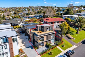 A modern two-story house with a balcony, a fenced yard, and a view of a residential area. - Modern 4BR Coastal Stay /Sea Views & Walk to Beach (Torbay)