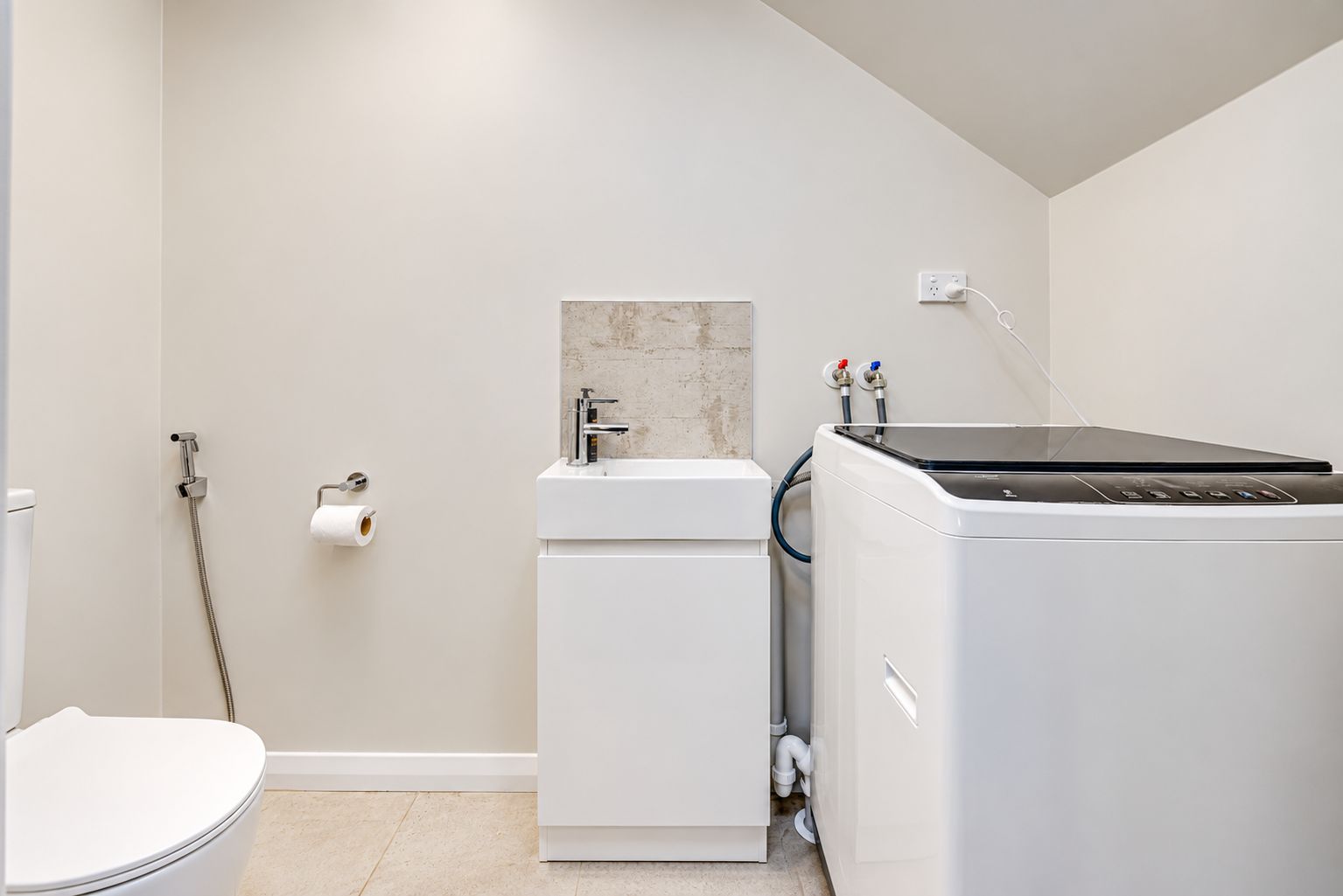 A modern bathroom with a toilet, a sink, and a washing machine.
