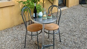Un patio con tavolo e sedie, una bottiglia di vino e un vaso con fiori.