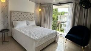 Una camera da letto moderna con un letto grande, una sedia, un tavolino e un balcone con tende.