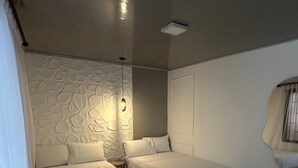 Una camera da letto con due letti, una parete testurizzata, una lampada a soffitto e uno specchio.