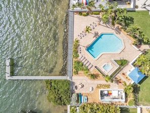 A pool area with lounge chairs, a small pool, and a dock extending into the water. - Summer Sands #217 2 Bedroom Home (Bradenton Beach)