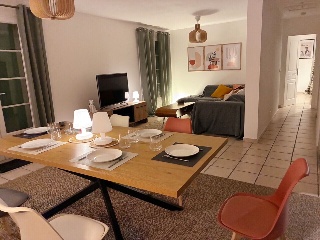 Un comedor con una mesa dispuesta para cuatro, un televisor y un sofá al fondo.