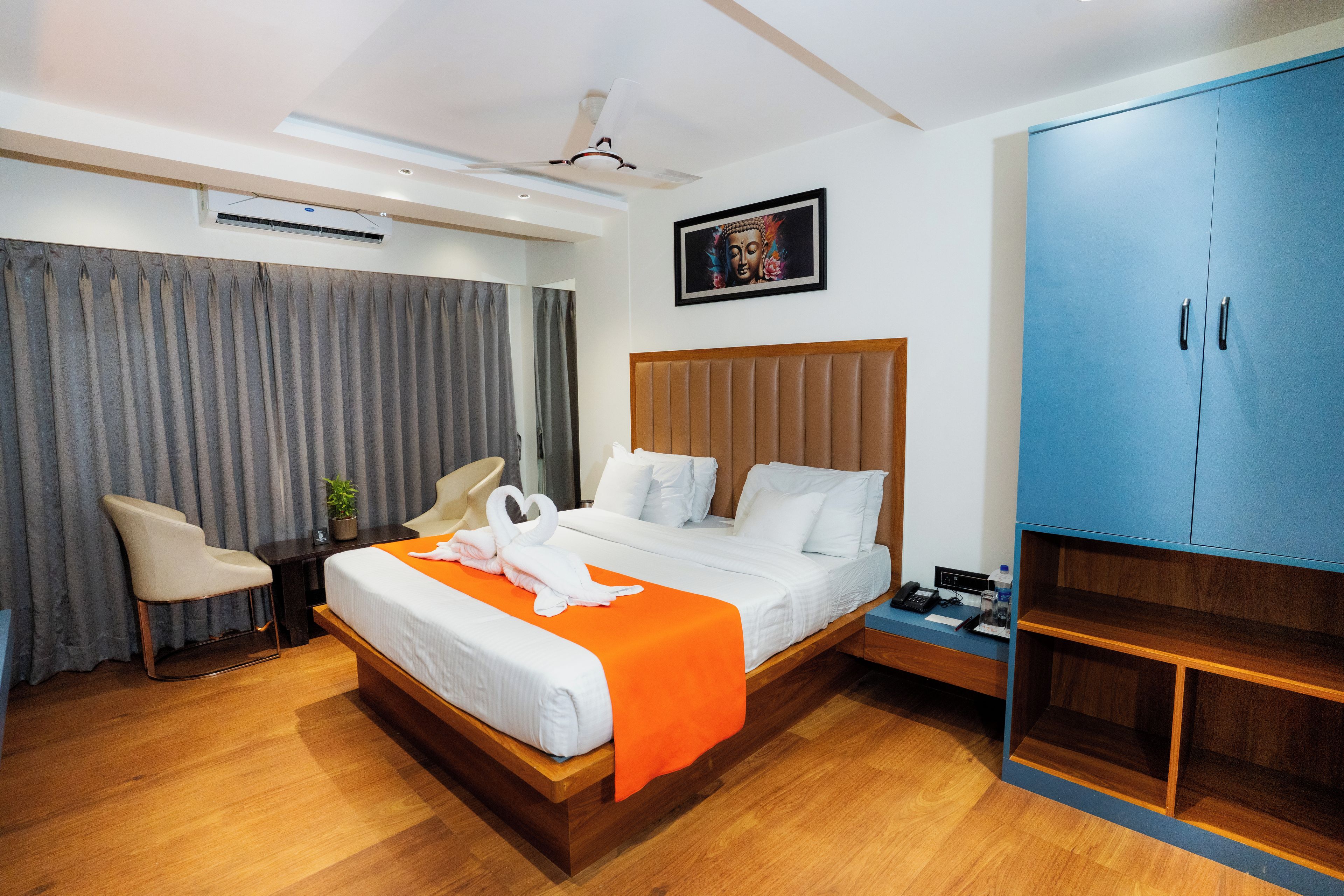 A hotel room with a bed, a desk, a chair, a wardrobe, and a ceiling fan.