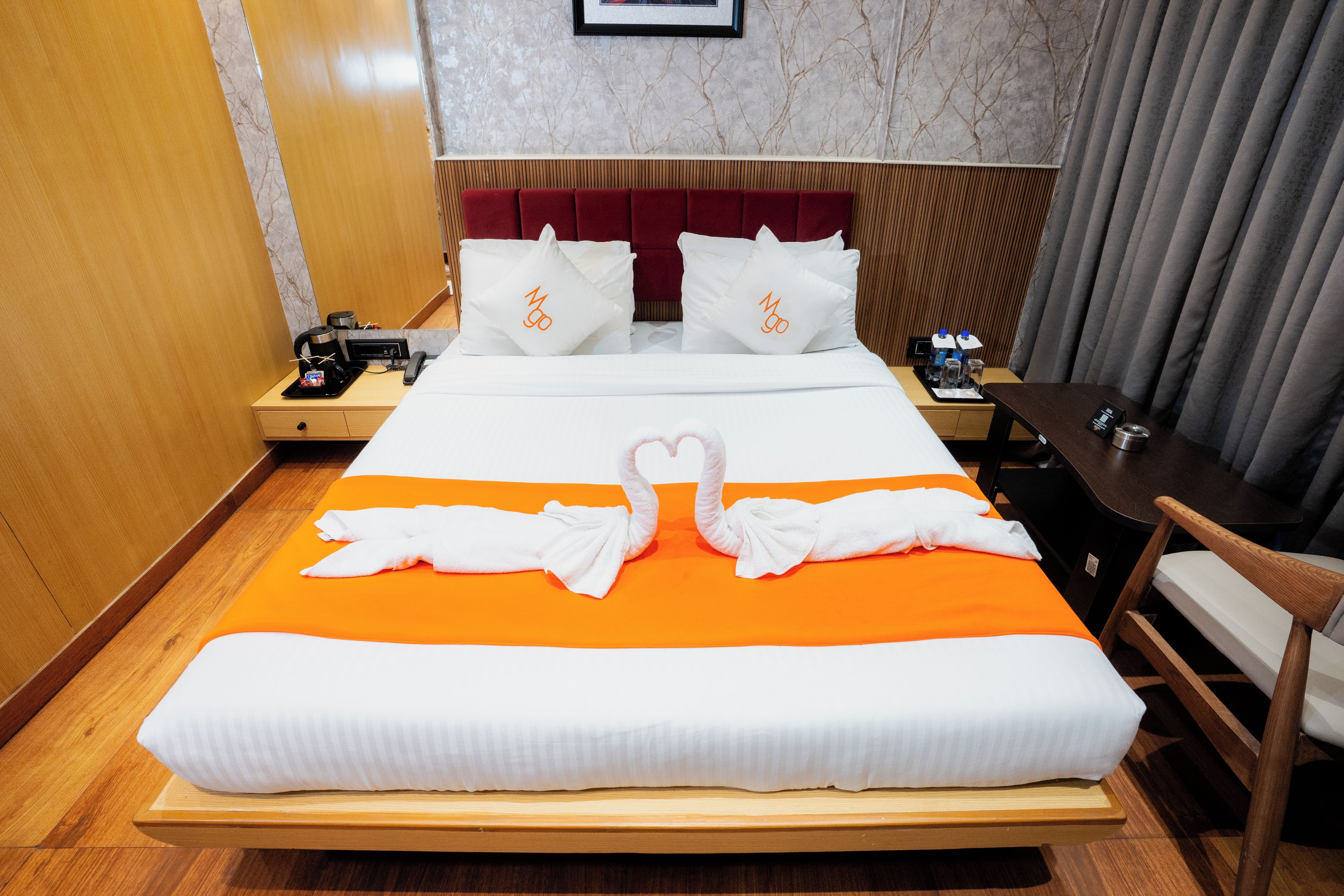 Quarto de hotel com cama, mesa de cabeceira, escrivaninha e cadeira.