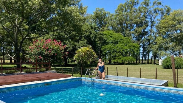 Une piscine avec une terrasse en bois et une personne portant un maillot de bain.