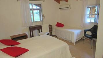 A room with two single beds, a desk, a chair, and an air conditioning unit.