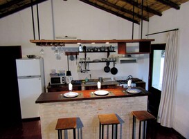Una cocina con una isla de madera, un refrigerador, una estufa y utensilios colgando.