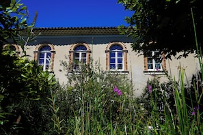 A building with arched windows and a tiled roof, surrounded by lush greenery. - La Magnanarié, a large family home in Provence (Villedieu)