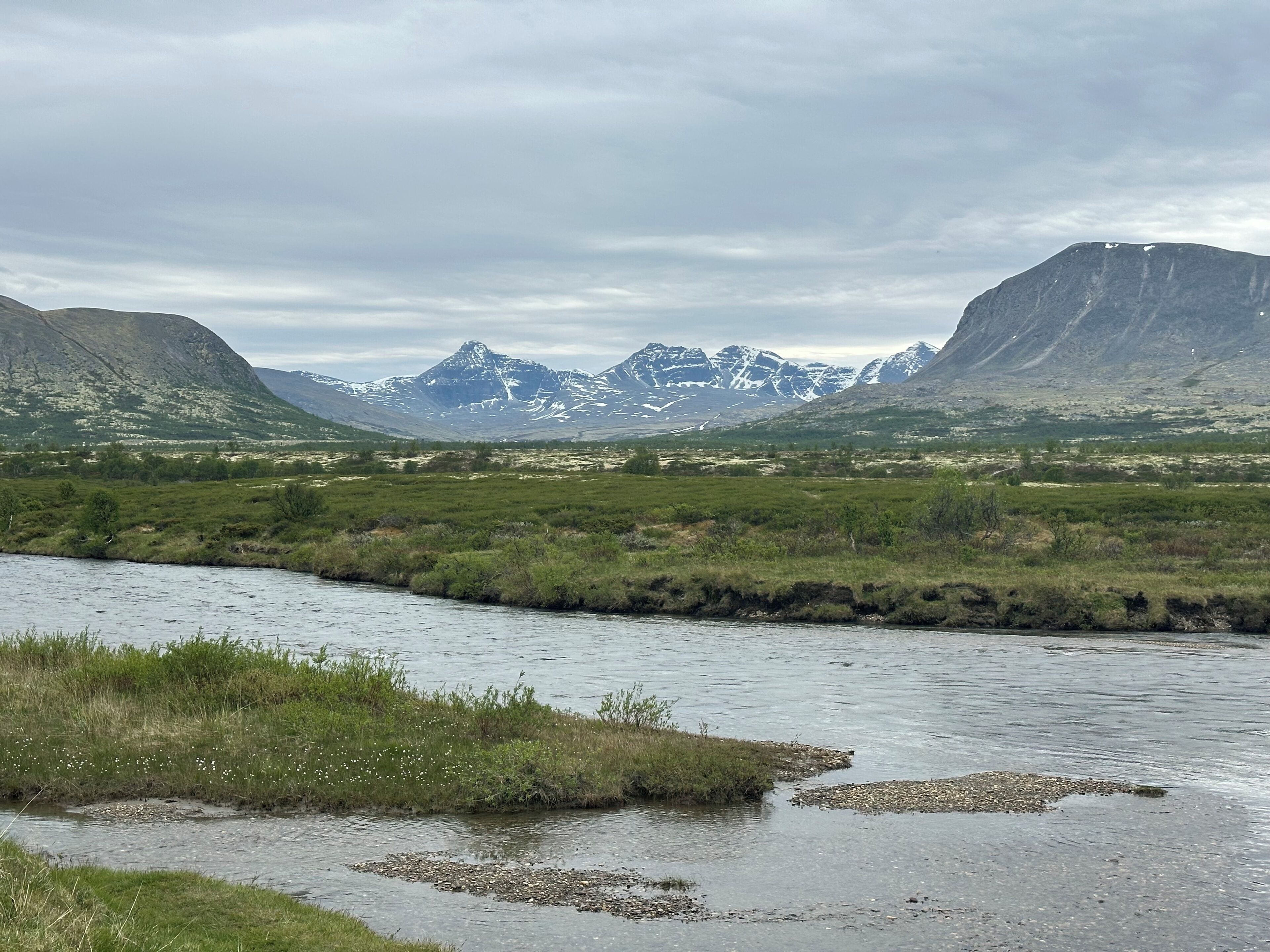 Une rivière qui traverse une vallée, avec des montagnes en arrière-plan.