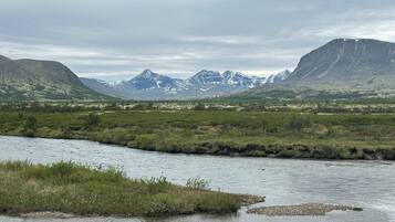 Une rivière qui traverse une vallée, avec des montagnes en arrière-plan.