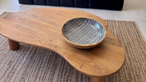 Ein modernes Wohnzimmer mit einem schwarzen Sofa, einem Holztisch und einem Essbereich im Hintergrund.