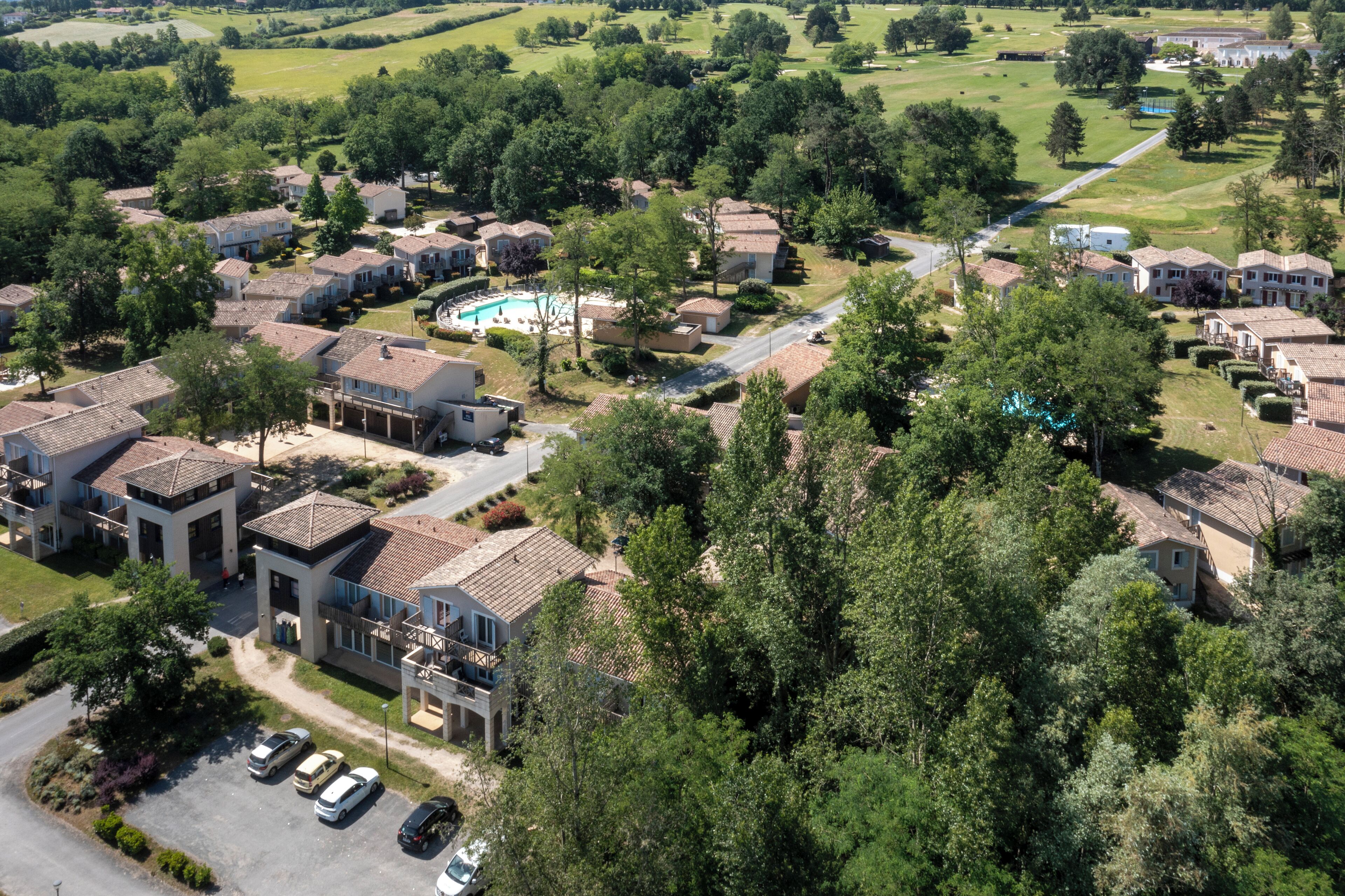 Un quartier résidentiel comprenant plusieurs maisons, une piscine et une route.