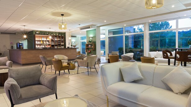 Un hall d’hôtel moderne doté d’un bar, d’un espace salon et de grandes fenêtres.