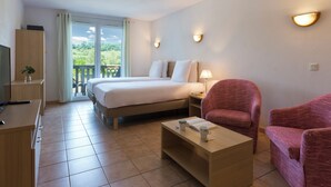 Une chambre d’hôtel équipée d’un lit, d’un bureau, d’une chaise, d’une table basse et d’un balcon avec vue.