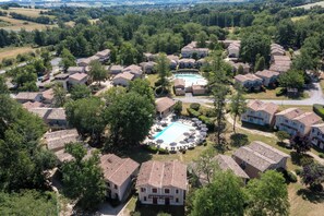 Vista aérea de una zona residencial con casas, piscina y follaje circundante.