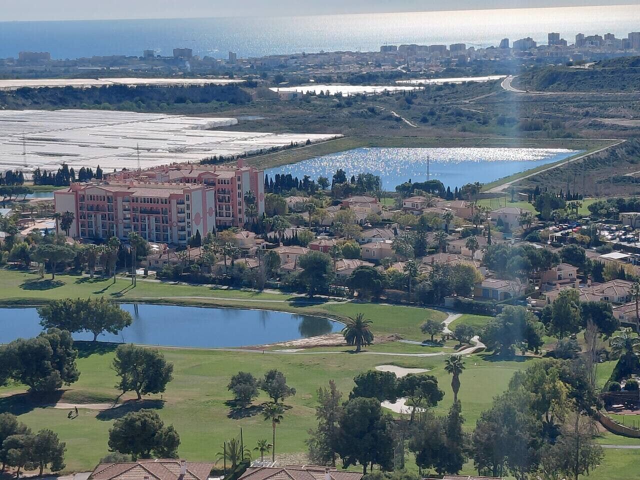 A residential area with a large building, multiple ponds, and a distant cityscape.