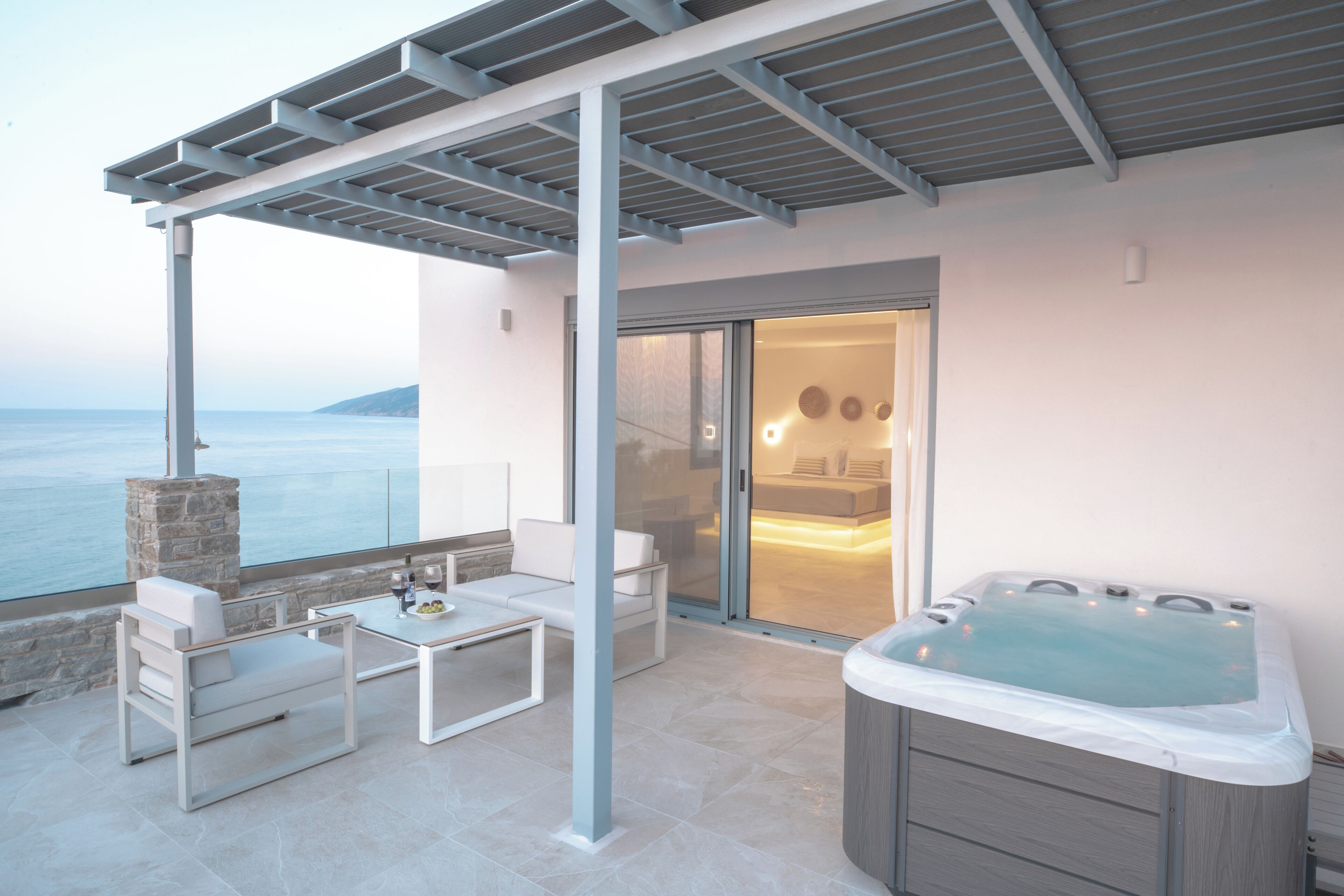En moderne udendørs terrasse med jacuzzi, siddepladser og havudsigt.