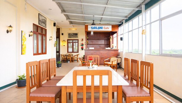 A restaurant with a high ceiling, wooden chairs, a central table, and a sign reading 'KAILANI Cafe'. - Siantar Hotel Parapat (Medan)