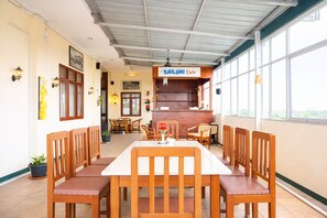 A restaurant with a high ceiling, wooden chairs, a central table, and a sign reading 'KAILANI Cafe'. - Siantar Hotel Parapat (Medan)