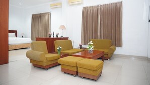 A hotel room with a bed, two sofas, a coffee table, a desk, and a lamp. - Siantar Hotel Parapat (Medan)