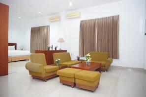 A hotel room with a bed, two sofas, a coffee table, a desk, and a lamp. - Siantar Hotel Parapat (Medan)