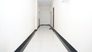 A corridor with white walls, a black baseboard, and a tiled floor. - Siantar Hotel Parapat (Medan)