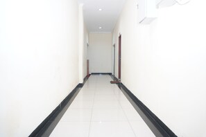 A corridor with white walls, a black baseboard, and a tiled floor. - Siantar Hotel Parapat (Medan)