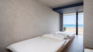 A minimalist bedroom with a bed, a view of the beach, and a large window. - nagisa awajishima (Awaji)