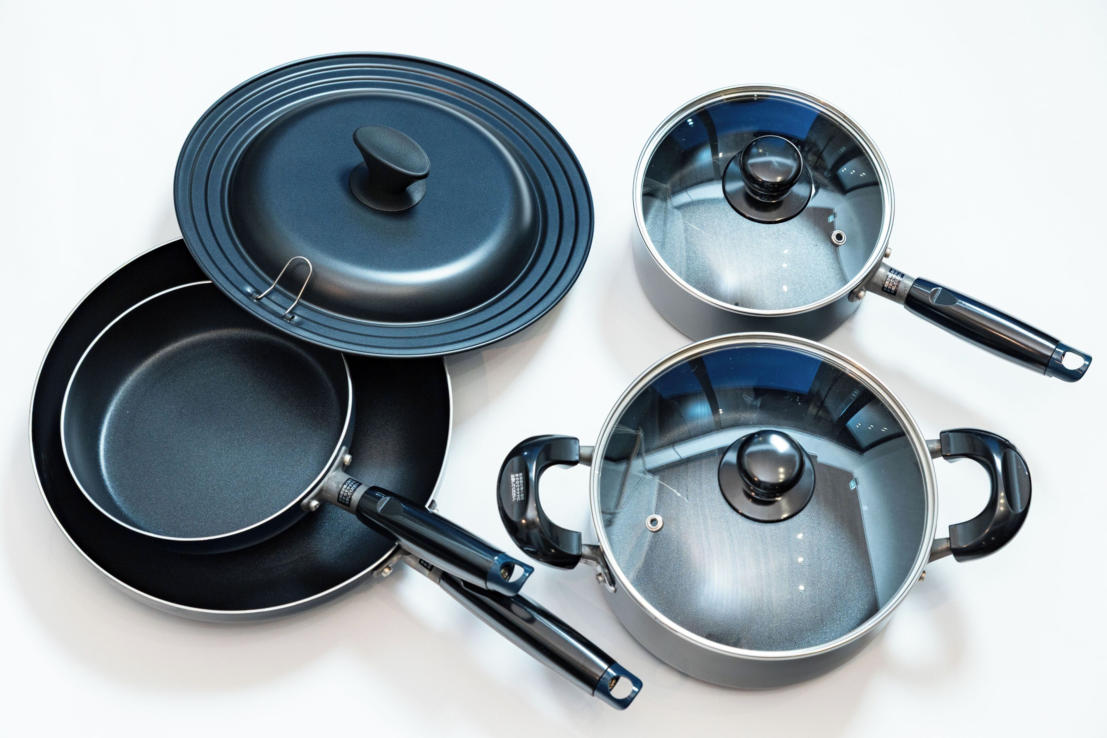 A set of cookware including a frying pan, a saucepan, and two pots with lids.